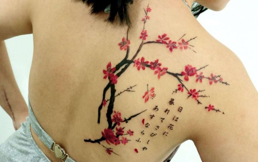 Tatuaje grande ramas sakura y letras