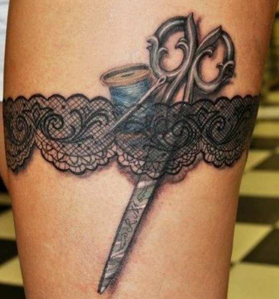 Tatuaje en el muslo - liguero, hilo, aguja y tijeras