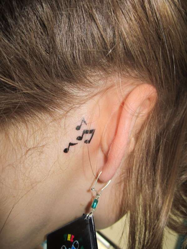 Tatuaje de notas musicales detrás de la oreja