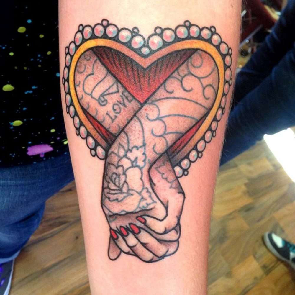 Tatuaje de corazón y manos tomadas