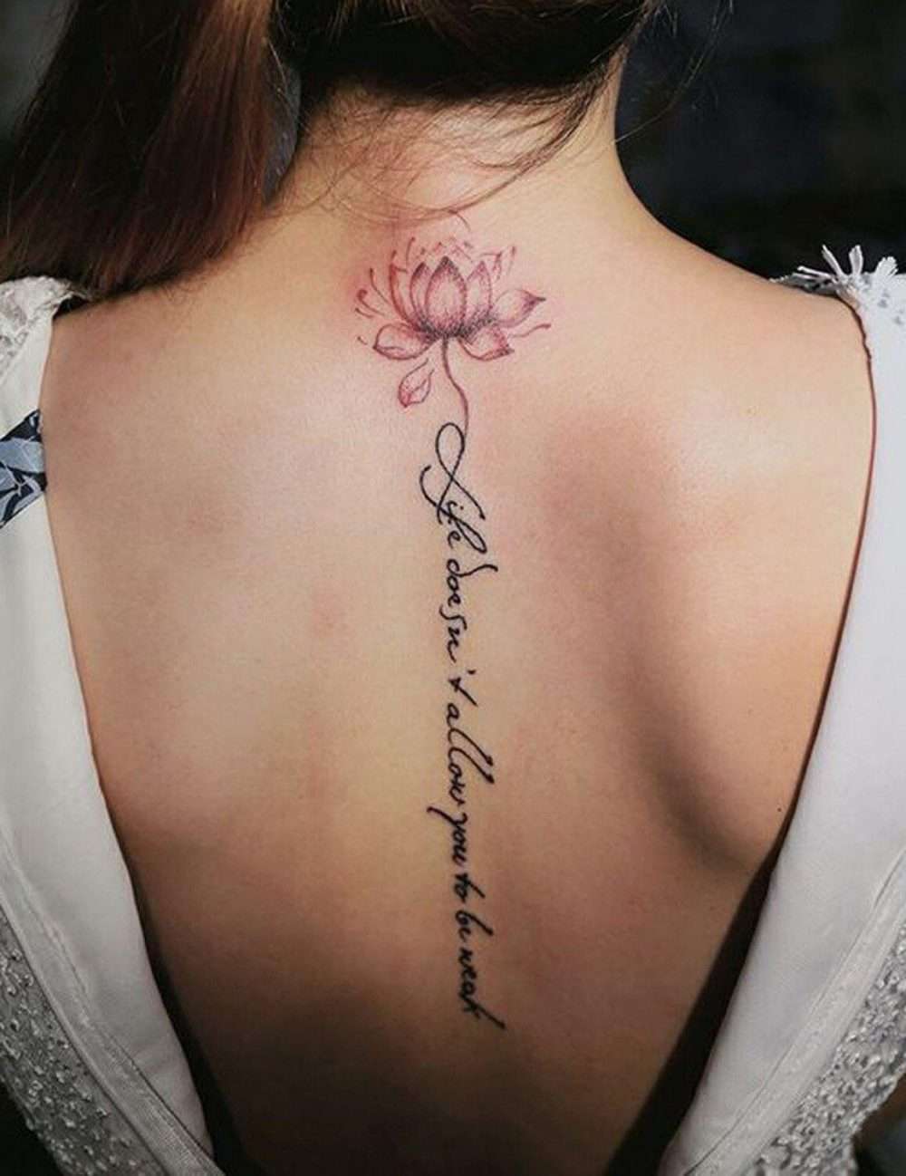 Tatuaje en la columna vertebral: flor de loto y frase