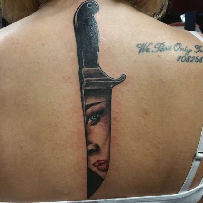 Tatuaje en la columna vertebral: cuchillo con rostro de mujer