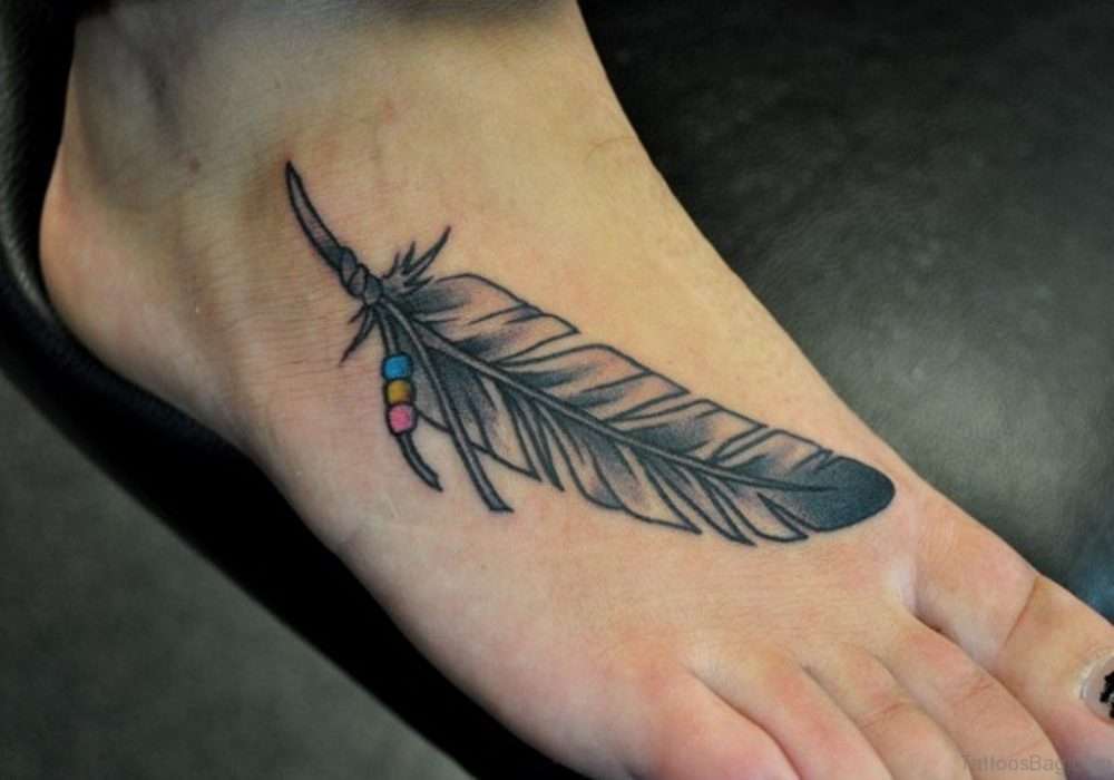 Tatuaje de pluma en el pie con detalle en color