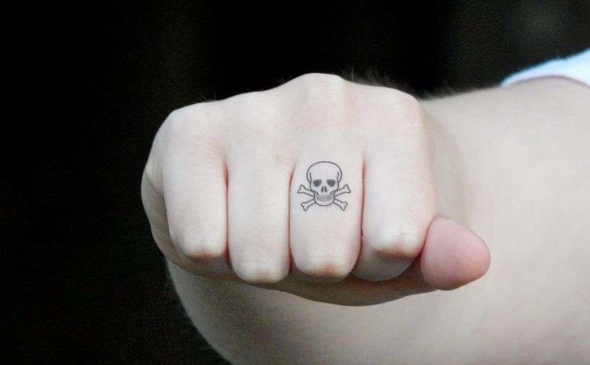 Tatuaje de calavera pequeña en el dedo