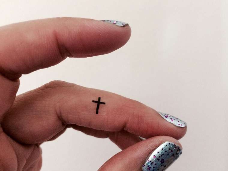 Tatuaje de cruz pequeña en el dedo