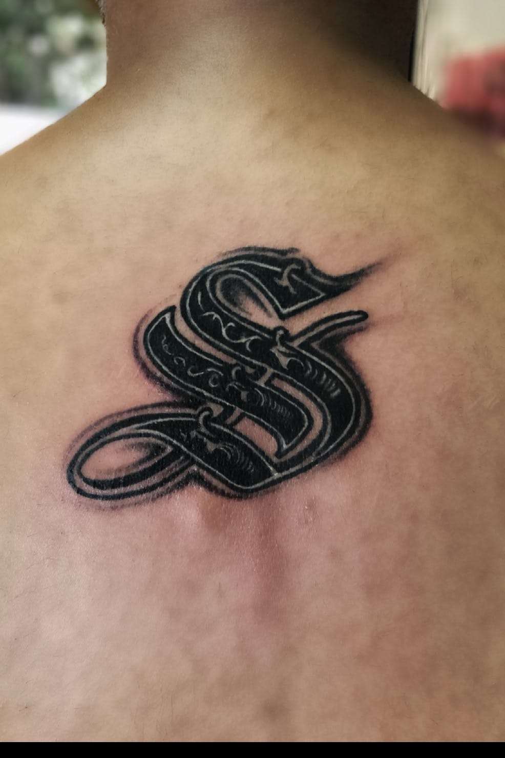 Tatuaje de letra "S" en color negro
